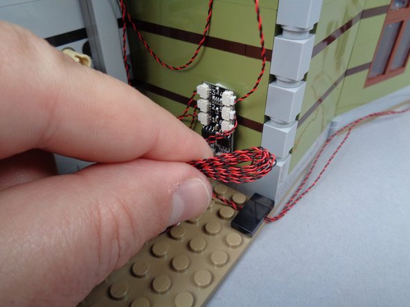 As shown in the photos for this step, tidy up the wires in the back of the mansion, making sure no loose wires can get pulled by or caught in any gears or other moving parts.