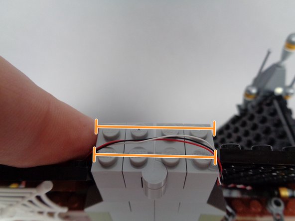 As shown by the orange lines in the third photo for this step, run the un-twisted segment of wire across both halves of the chimney, making sure to pass the wire BETWEEN, not on top of, studs.