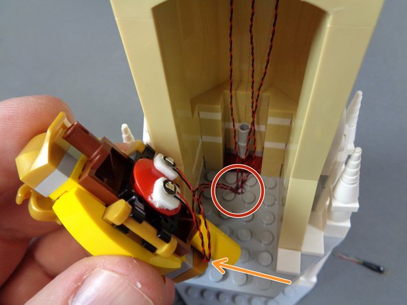 As shown by the orange arrow in the first photo, wrap the two mirror light wires around the base of the mirror once, then pass the wires through the hole in the floor as shown by the red circle.