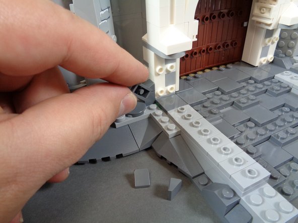 As shown in the photos for this step, next you will remove sections from the front of the castle and the rockwork by the front door.  This is to prepare for re-attaching the two front torches and hiding their wires.