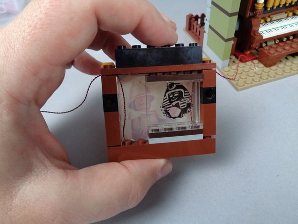 As shown by the photos for this step, re-assemble the painting frame by placing the Sphinx panel back behind the painting and re-attaching the bottom frame.