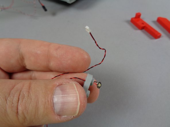 As shown in the second photo for this step, insert the first LED light wire through the hole in the light bluish gray plate.