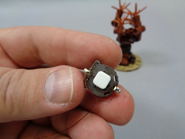 As shown in the first photo, take one of the sticky squares and attach it to the back side of the battery pack.