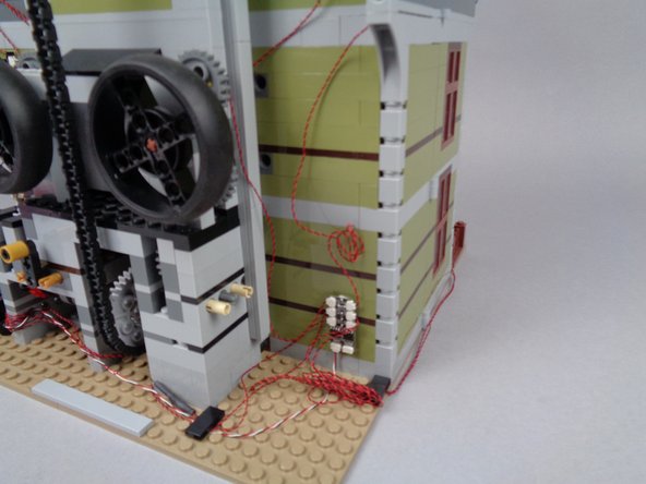 As shown in the photos for this step, tidy up the wires in the back of the mansion, making sure no loose wires can get pulled by or caught in any gears or other moving parts.