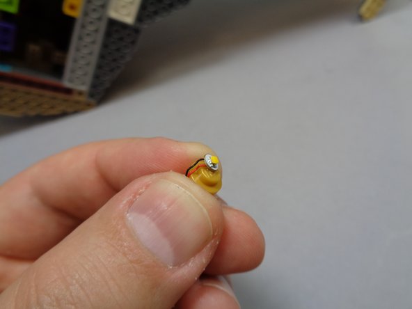 Using your fingernail, bend the light wire down the side of the gold lamp base stud.  This will make it easier to re-attach the transparent top.