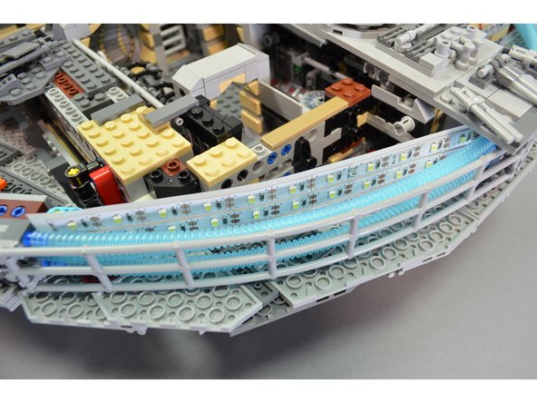As shown in the second photo for this step, mount the engine lighting assemblies behind the blue engine tubes so the wires for each assembly face toward the center of the Falcon.