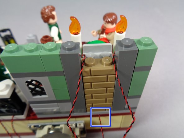 As shown in the third photo, re-attach the main wall section and pass the two candle light wires back through the gap in the chimney.