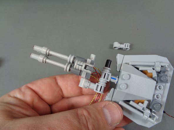 As shown in the photos for this step, mount the pre-lit laser cannon so its wires pass to the lower side of the turret.