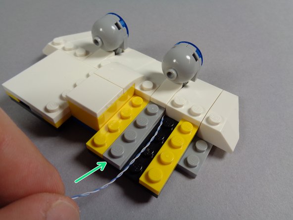 As shown by the orange arrows in the first photo, make sure the LED light wire runs to the side of the studs behind the light.  Wires must never run on top of any studs, or they can get pinched or broken when parts are attached on top of them.