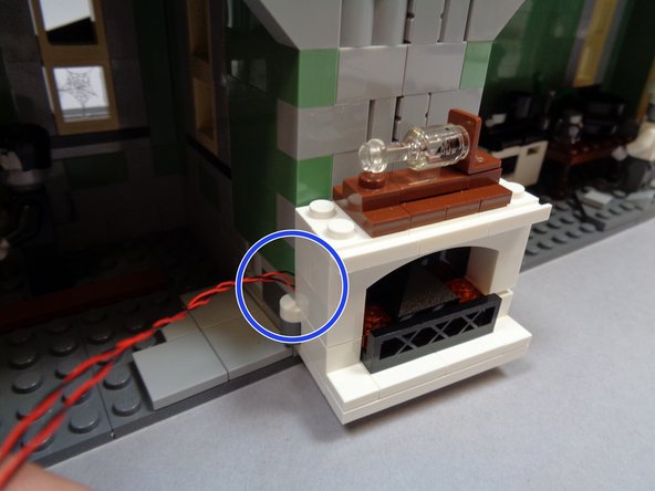 As shown by the red circle in the second photo and the blue circle in the third photo, make sure the two light wires pass between the fireplace and the wall ABOVE the hinge.