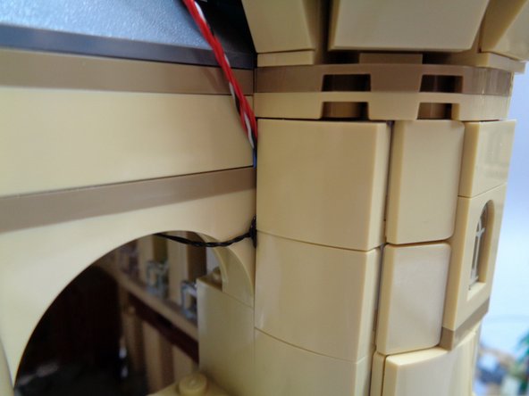 As shown in the second and third photos, you can remove one or two of the tan slopes on the back of the tower and tuck the excess wire into the space under the slopes.