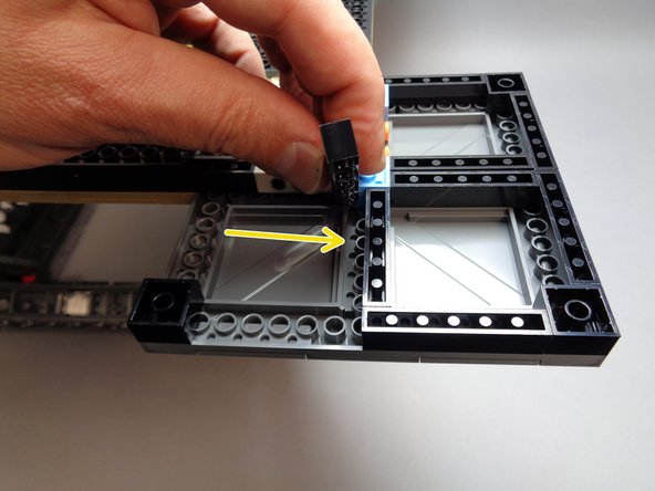 As shown by the yellow arrow in the second photo for this step, place the 1x6 brick you just removed in the center of the foot base.