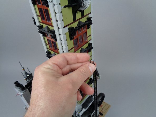 As shown in the photos for this step, disconnect the elevator chain and let it fall away from the upper tower section.