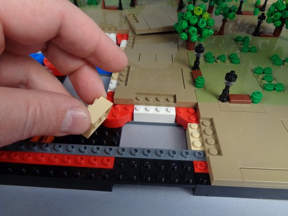 As shown in the photos for this step, remove the 2x3 tan brick under Panel 2R and run the control cable between the studs on the black bottom plate, then re-attach the tan brick on top of the cable.