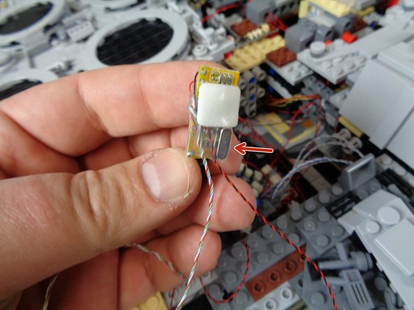 As shown in the second photo, attach a large sticky square to the back side of the remote receiver.  As shown by the red arrow in the second photo, you can tell the back side of the receiver by the rectangular metal crystal mounted on the back.