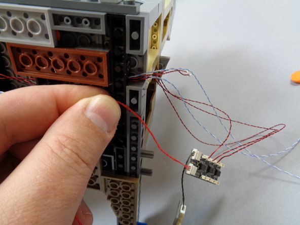As shown in the second photo, take the red wire from the BRANCH09X adapter board and run it where you removed the large plate in the previous step.