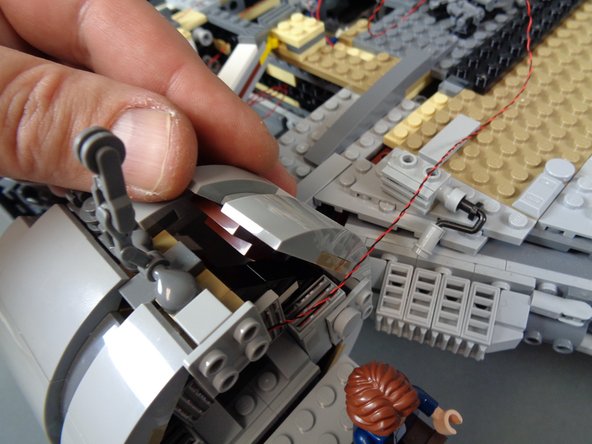 As shown in the second and third photos, lift up the top sections of the cockpit passage and feed the light wire through the opening toward the back of the cockpit.