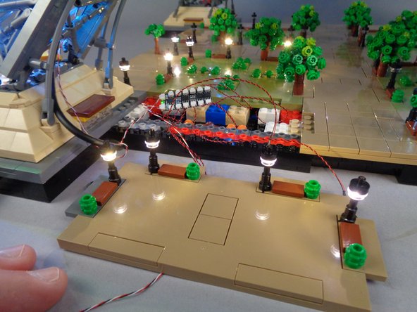 As shown in the second photo for this step, the four lamp posts should turn on.  You should now have all 12 lamp posts in Section 1 turned on.