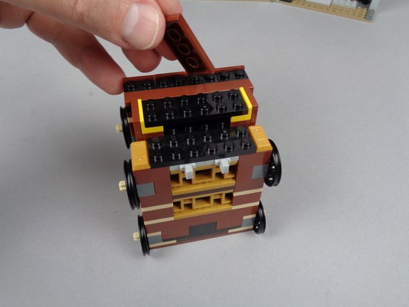 As shown in the photos for this step, remove two LEGO pieces from the top of your elevator.  When you have removed these top two parts, thew yellow side brackets should be visible as shown by the orange arrows in the third photo.