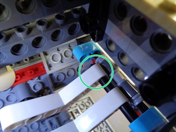 As shown by the green circle in the second photo, press the axle through the second arm.