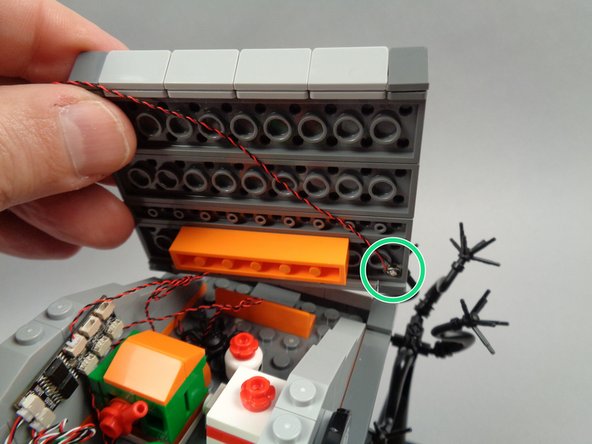 As shown in the first photo for this step, re-attach the first roof section.