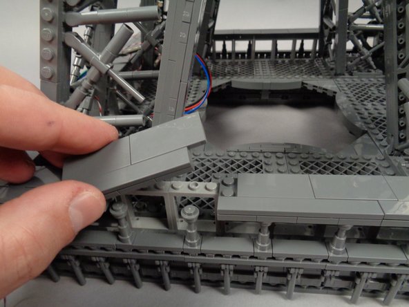 Tuck the adapter board into the base of the second pillar, then remove a section from the outer frame as shown in the first photo for this step.
