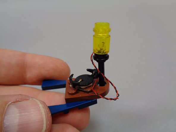Mount the battery holder in the base of the boat, and attach the lantern assembly to the top of the black rod as shown in the third photo.