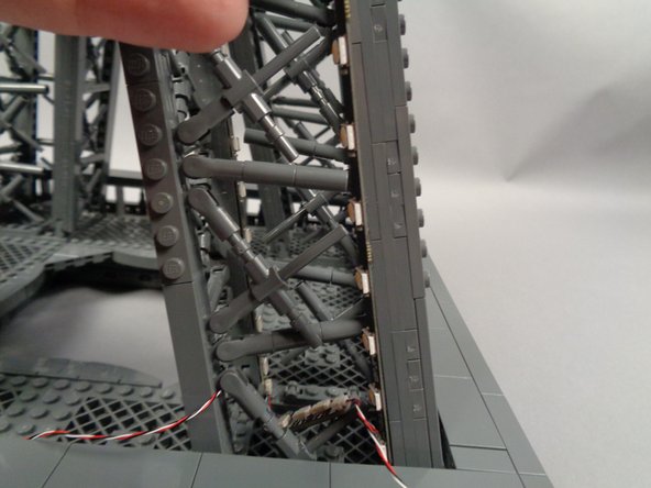 As shown in the photos for this step, attach the next light strip (shown by the yellow line in the second photo) and make sure it is firmly attached to the pillar.