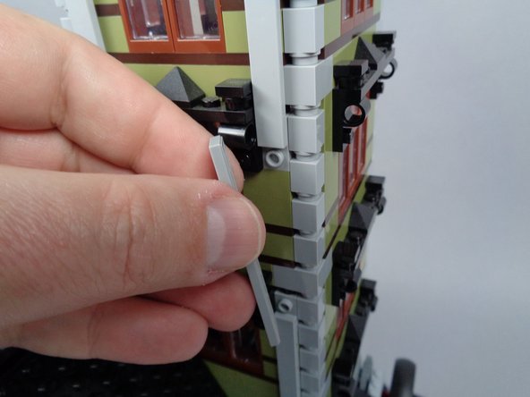 As shown in the photos for this step, re-attach the long LEGO tiles on three sides of the tower to secure it.