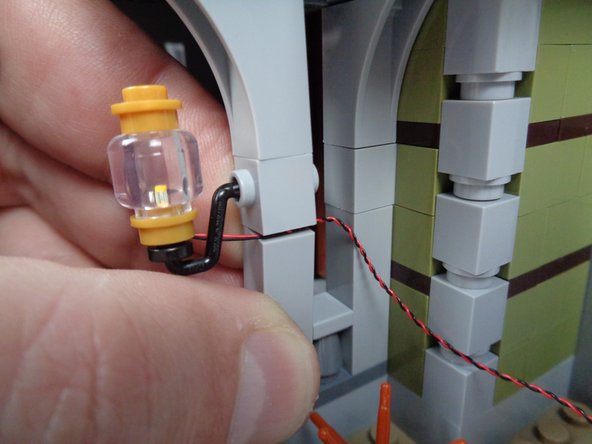 As shown in the second photo for this step, carefully bend the front porch column outward, so you can pass the wire through the gap between the bricks.