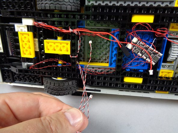 Because the lightbar control wires are long, you can loop them several extra times around the black Technic frame as shown by the purple arrows in the second photo.