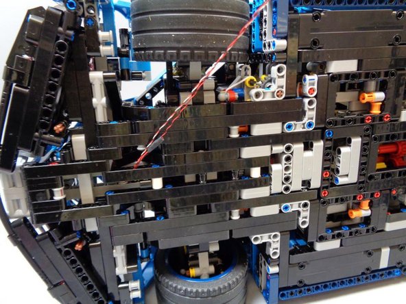 In this step, as shown in the three photos, you will continue routing the two wires toward the back of the car.