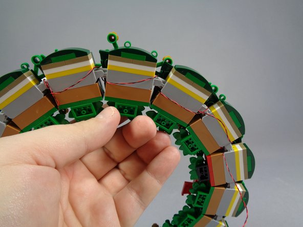 When looping the wires over the top side of the wreath, make sure to hide them under the leaf/foliage parts.  This can be tricky, and the leaves will want to separate from the wreath, so take your time.