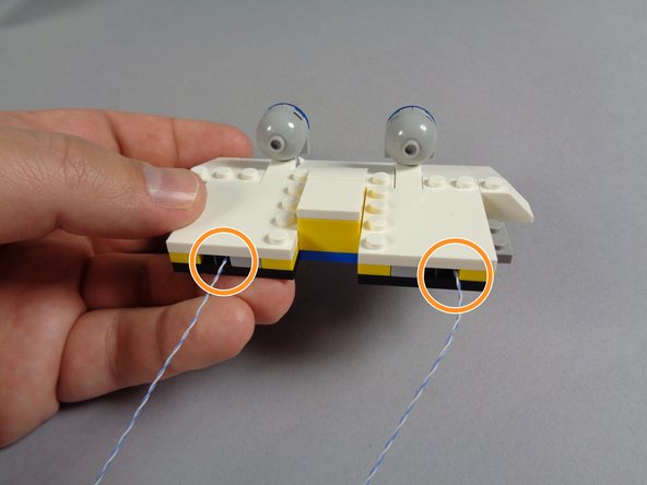 As shown by the orange circles in the second photo, both LED light wires should pass under the large white plates inside the hollow channel underneath the plate, and not be caught on any studs.