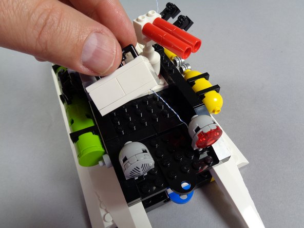 As shown in the first photo for this step, remove the white square assembly from the roof to allow the light wires to pass beneath.  Set the white square assembly aside for now.