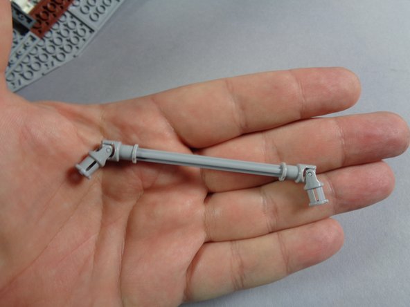 As shown in the photo, take the longer (9-stud length) light bluish gray axle and attach the two light bluish gray universal joints, one on each end of the axle.