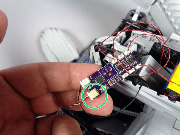 As shown by the green circle in the first photo for this step, connect the 3-wire plug that connects to the eye assembly to the other large plug on the effect controller.