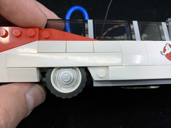 As shown in the three photos for this step, re-attach the side windows, dark bluish gray tiles, and while wheel well cover you removed in earlier steps.