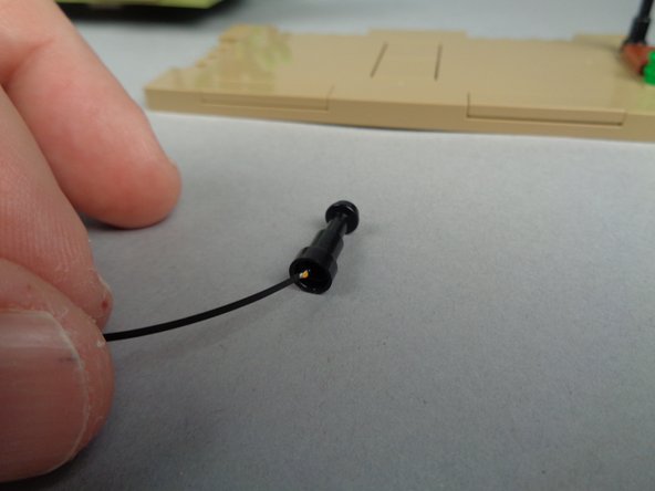 As shown in the two photos for this step, carefully pass the end of the Microflex LED light up through the center of the lamp post until the small LED chip is visible above the top as shown in the second photo.