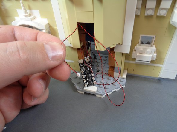 As shown in the first photo for this step, pull the bedroom light wire out through the front of the castle.