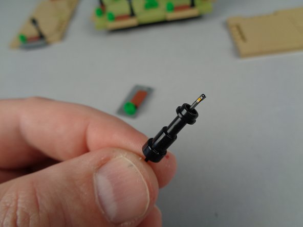 As shown in the two photos for this step, carefully pass the end of the Microflex LED light up through the center of the lamp post until the small LED chip is visible above the top as shown in the second photo.