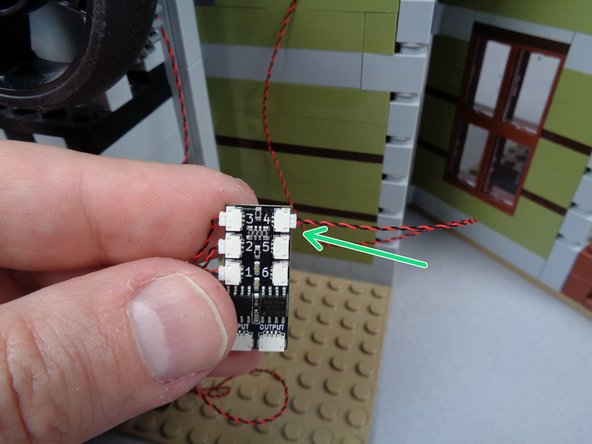 As shown by the green arrow in the second photo for this step, connect the wire for the second green LED light to plug #4 on the second BRANCH06X adapter board.