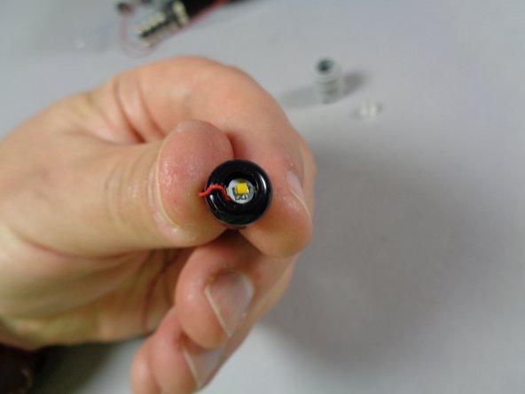 As shown in the second photo for this step, lower the light inside the black part.  The light should still be visible, but should be lowered far enough to allow the round 1x1 transparent plate to be re-attached.