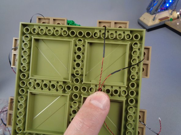 In order to prevent damage to the LED light wires when re-attaching the large plates, you can use the two white 2x2 bricks you removed in Step 65 to hold the wires, as shown in the photos for this step.