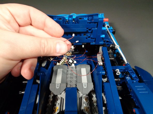 As shown in the first photo for this step, carefully reach inside the main frame of your Bugatti and pull out the two light wires from the strips you mounted earlier.