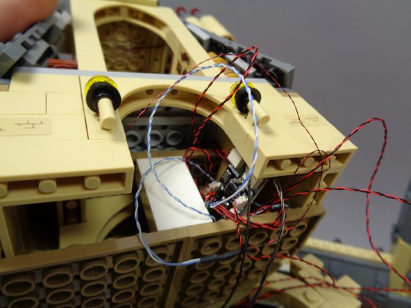 After all 9 plugs are used up on the BRANCH09X adapter board, tuck the board and all of the light wires into the space beneath Dumbledore's office, as shown in the third photo.