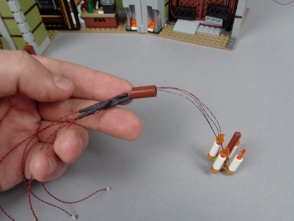 As shown in the first photo for this step, you should now have all four LED light wires passed through the brown LEGO connector part.