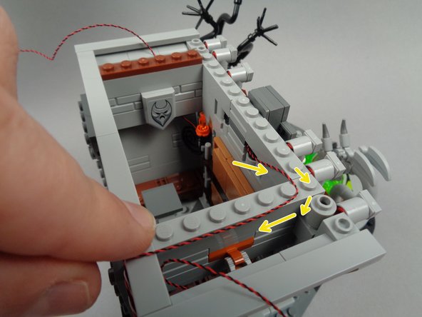 As shown by the yellow arrows in the second photo for this step, route the banner light wires to the right and around the first stud of the inner wall, then toward the back of the hall.