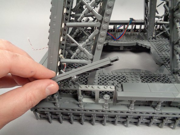Tuck the adapter board into the base of the third pillar, then remove a section from the outer frame as shown in the first photo for this step.