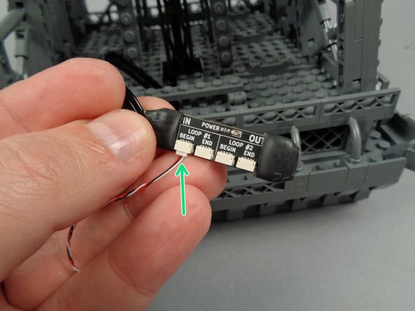 As shown by the green arrow in the first photo for this step, take one of the control cables and connect one end to the plug labeled "BEGIN" in the "LOOP #1" section of the inter-level connecting board.